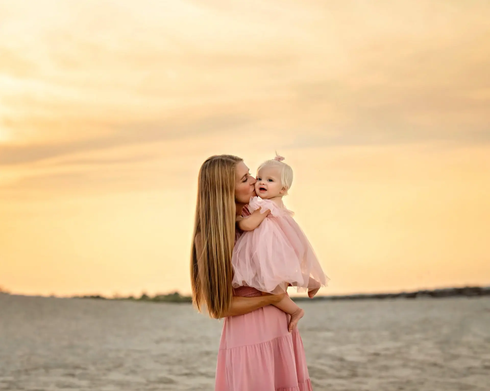 Mother kissing her baby at sunset